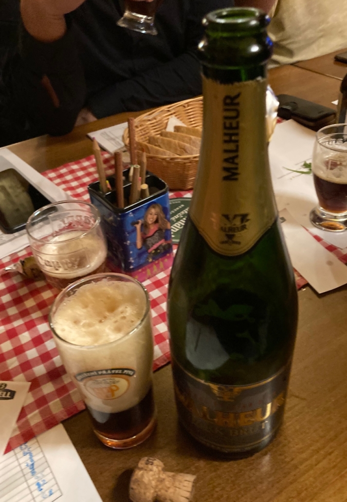 Otevřená láhev piva Malheur Dark Brut na stole v restauraci
