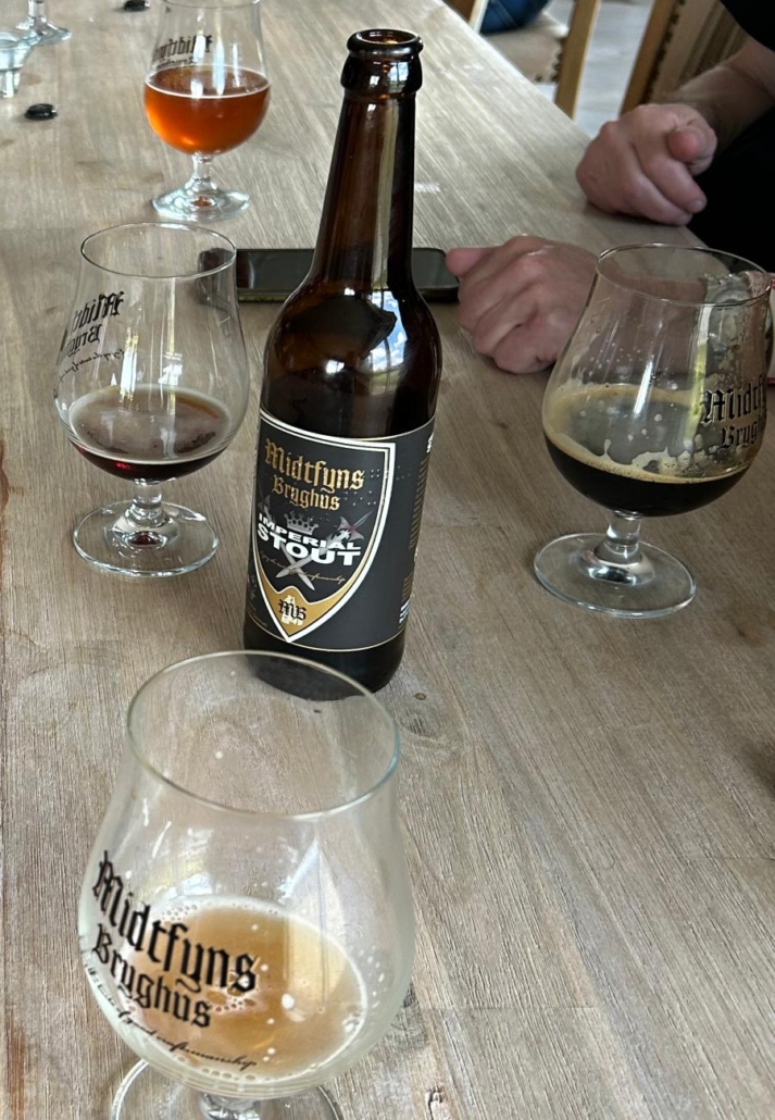Sklenice piva Midtfyns Imperial Stout s tmavou pěnou na dřevěném stole