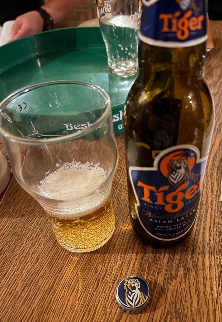 Vychlazená sklenice piva Tiger Lager Asian na stole v hospodě